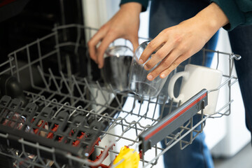 young woman putting a dishwasher in her house after a meal. Woman doing housework.