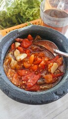 ingredients for making typical Sundanese spicy chili sauce in a pestle; red chilies, fat chilies, garlic and tomatoes in large quantities