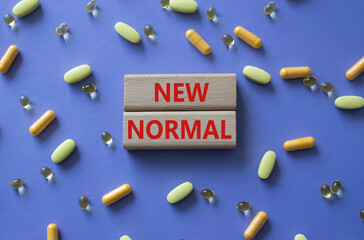 New normal symbol. Wooden blocks with words New normal. Beautiful purple background with pills....