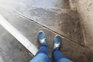 View from above on legs in moccasins on background of old wooden steps. Women's feet in blue shoes...