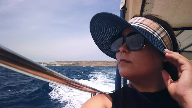 Middle agged woman with sunglasses and hat enjoing boat ride. High quality 4k footage