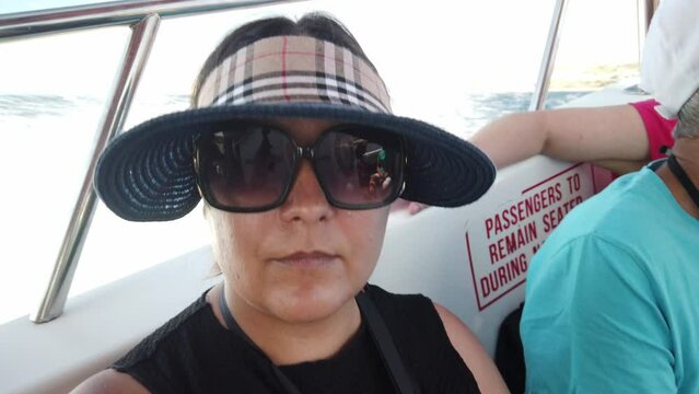 Middle agged woman with sunglasses and hat enjoing boat ride. High quality 4k footage