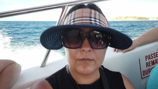 Middle agged woman with sunglasses and hat enjoing boat ride. High quality 4k footage