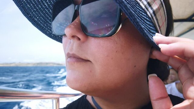 Middle agged woman with sunglasses and hat enjoing boat ride. High quality 4k footage