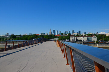 Obraz premium New brigde in Warsaw, Poland. Pedestrian and bicycle footbridge over the Vistula River. Warsaw skyline