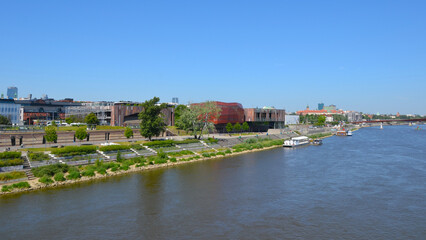 Fototapeta premium Vistula Boulevards promenade on the west side of the Vistula river. Popular place for weekend walks. View from Swietokrzyski bridge. Warsaw, Poland