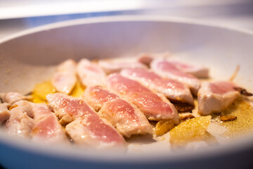 a fresh and natural turkey breast cut into fillets is cooked in a white granite pan with a little organic extra virgin olive oil and onion slices