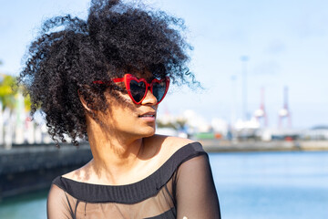 Non-binary person with afro hair and heart-shaped sunglasses, looking to the right