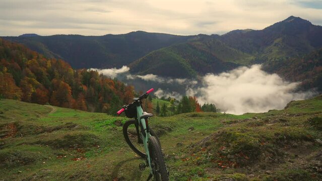 Electric bike stands on high mountain above clouds in autumn in Bavarian Alps. Brightly colored mountain e bike against German alps in higher than clouds. Theme travels in alpine by eletro cycle. 