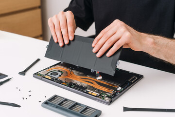 Cropped shot of repairman change battery on modern laptop