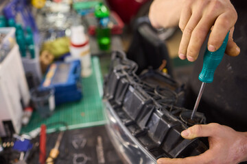 showing hands effectively repairing a car headlight in a workshop environment
