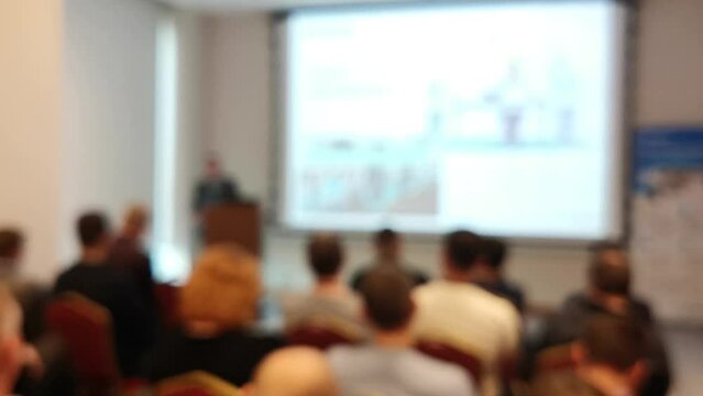 Blurred defocused footage with back view of audience in a business conference or seminar. Audience listens to the lecturer at the conference in auditorium.