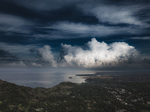 storm clouds over ocean with rolling hills below