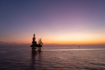 Aerial view of silhouette offshore jack up drilling rig during sunset - oil and gas industry.