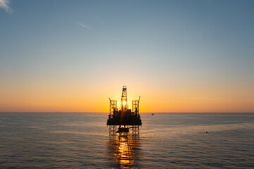 Aerial view of silhouette offshore jack up drilling rig during sunset - oil and gas industry.