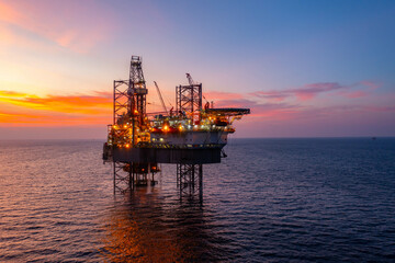 Aerial view of silhouette offshore jack up drilling rig during sunset - oil and gas industry.