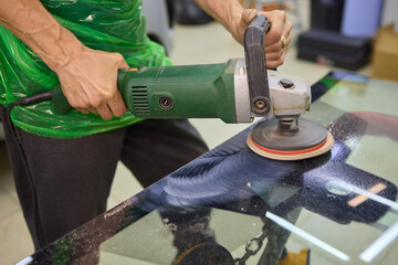 A professional technician expertly polishes glass surfaces in a workshop with precision