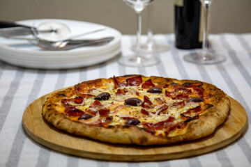 Calabrian sausage pizza served on a round board and set table