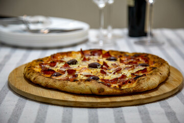 Calabrian sausage pizza served on a round board and set table