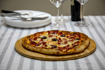Calabrian sausage pizza served on a round board and set table