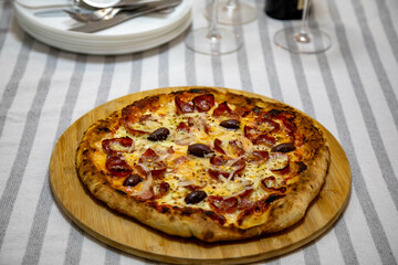 Calabrian sausage pizza served on a round board and set table