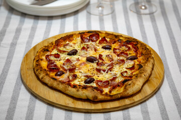 Calabrian sausage pizza served on a round board and set table