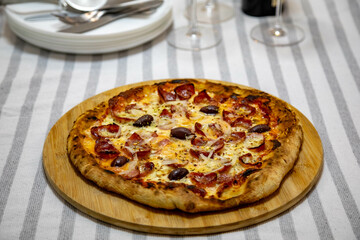 Calabrian sausage pizza served on a round board and set table