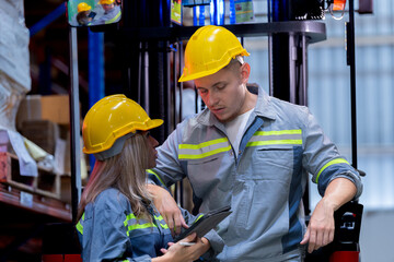 Two male and female factory checkers are discussing work on a warehouse truck. While working in a warehouse for industrial products