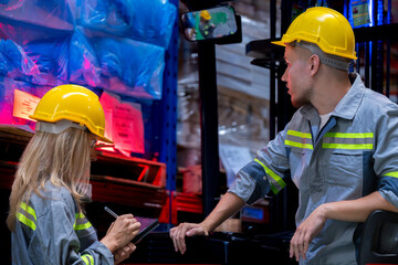 Two male and female factory checkers are discussing work on a warehouse truck. While working in a...