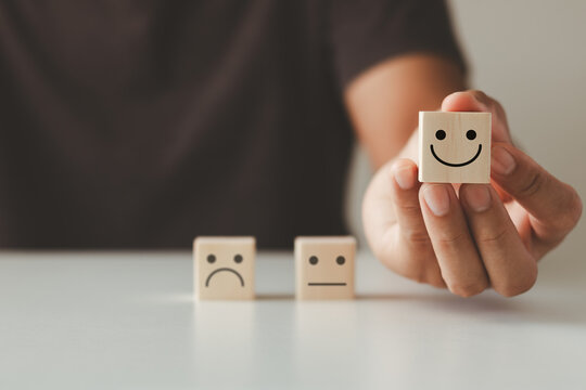Customer satisfaction concept.  Hand of a businessman chooses a smiling face on a wooden cube block. Customer services best excellent business rating experience.