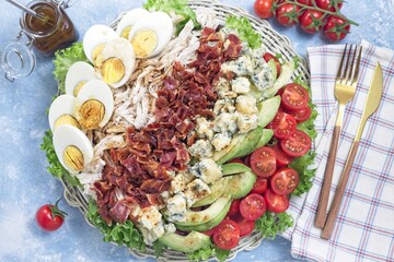Cobb salad with greens, tomato, avocado, blue cheese, bacon, chicken and eggs, horizontal top view