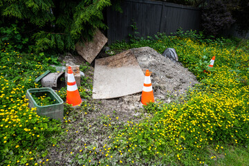 Fototapeta premium Work in progress, underground utility dug up for repair and covered by plywood and marked by orange safety cones for protection 
