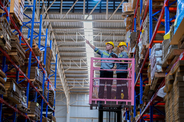 workers man and woman using a hydraulic scissor lift to check stock near the shelves warehouse....
