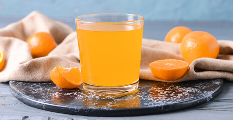 Glass with tasty mandarin juice on color wooden background