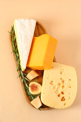 Wooden board with tasty cheese and fig on beige background