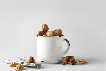 Mug of tasty walnuts on grey background