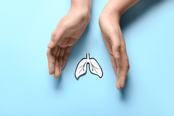 Female hands with paper lungs on blue background