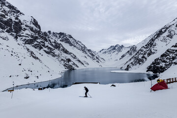 man skiing in the snow in front of Laguna Del Inca in Chile.