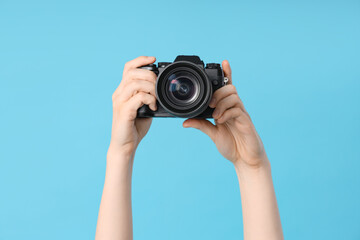 Female hands with modern camera on blue background