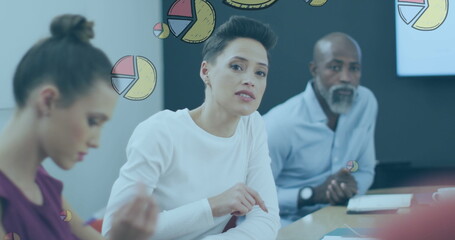 Image of pie graph icons against caucasian woman discussing with her colleagues at office