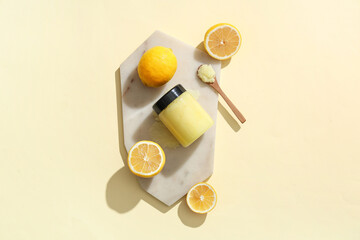 Board with body scrub and lemons on color background