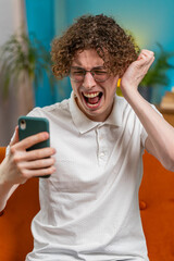 Sad displeased Caucasian man using smartphone typing browsing, loses becoming surprised sudden...