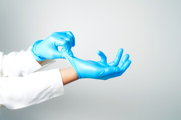 Two hands of a man wearing nitrile blue gloves on a white background