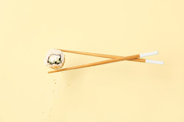 Tasty flying sushi roll and chopsticks on beige background