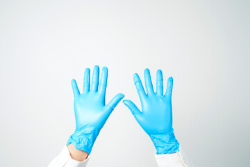 Doctor's hand in blue medical gloves holding an object on a white background