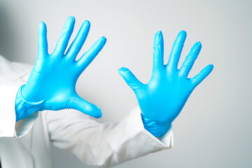 Doctor's hand in blue medical gloves holding an object on a white background