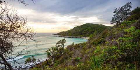 sunset over a beautiful cameral hidden little cove bay covered with greenery in Noosa National...