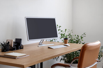 Modern workplace with computer monitor, coffee cup and houseplant in office