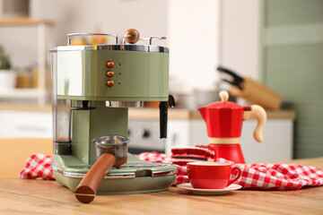 Modern coffee machine, cup of espresso and cake on wooden table in kitchen