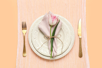 Stylish table setting with beautiful tulip on orange background